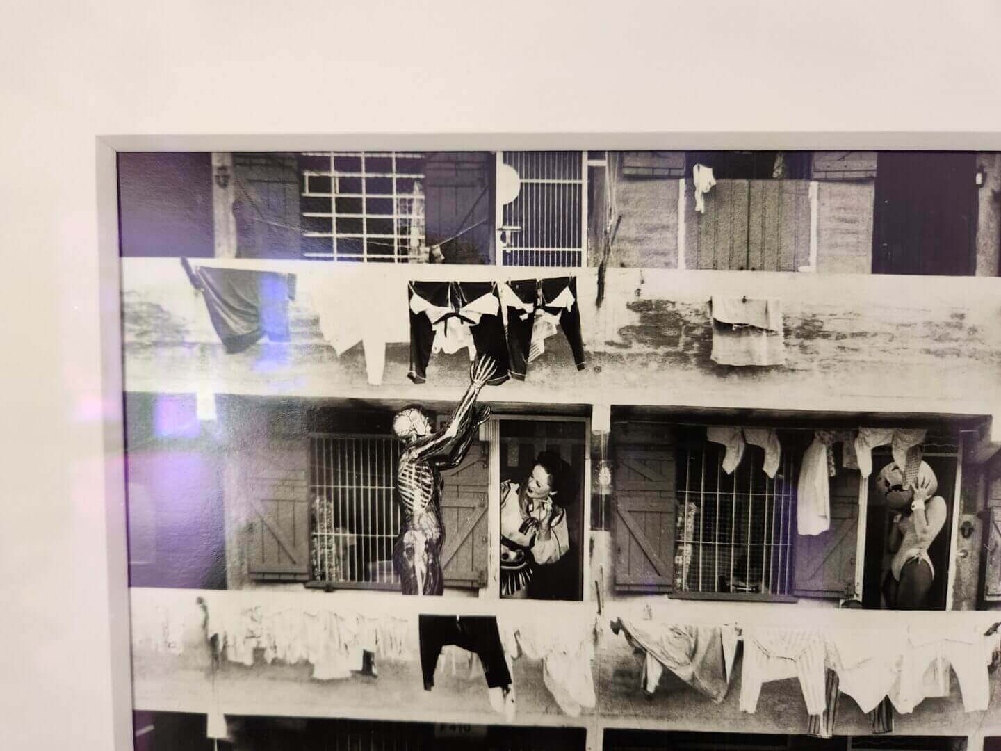 Black and white photograph of a building facade with figures and laundry, only available at Chelsea Art Group - New York City top trusted art advisers.